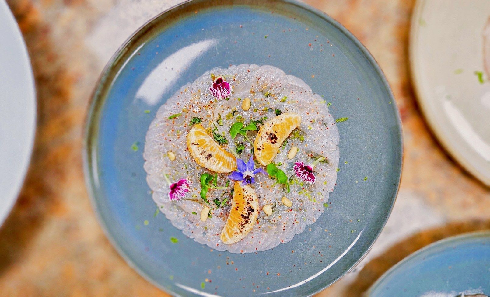 Plated course with citrus segments on blue ceramics, seen from above.