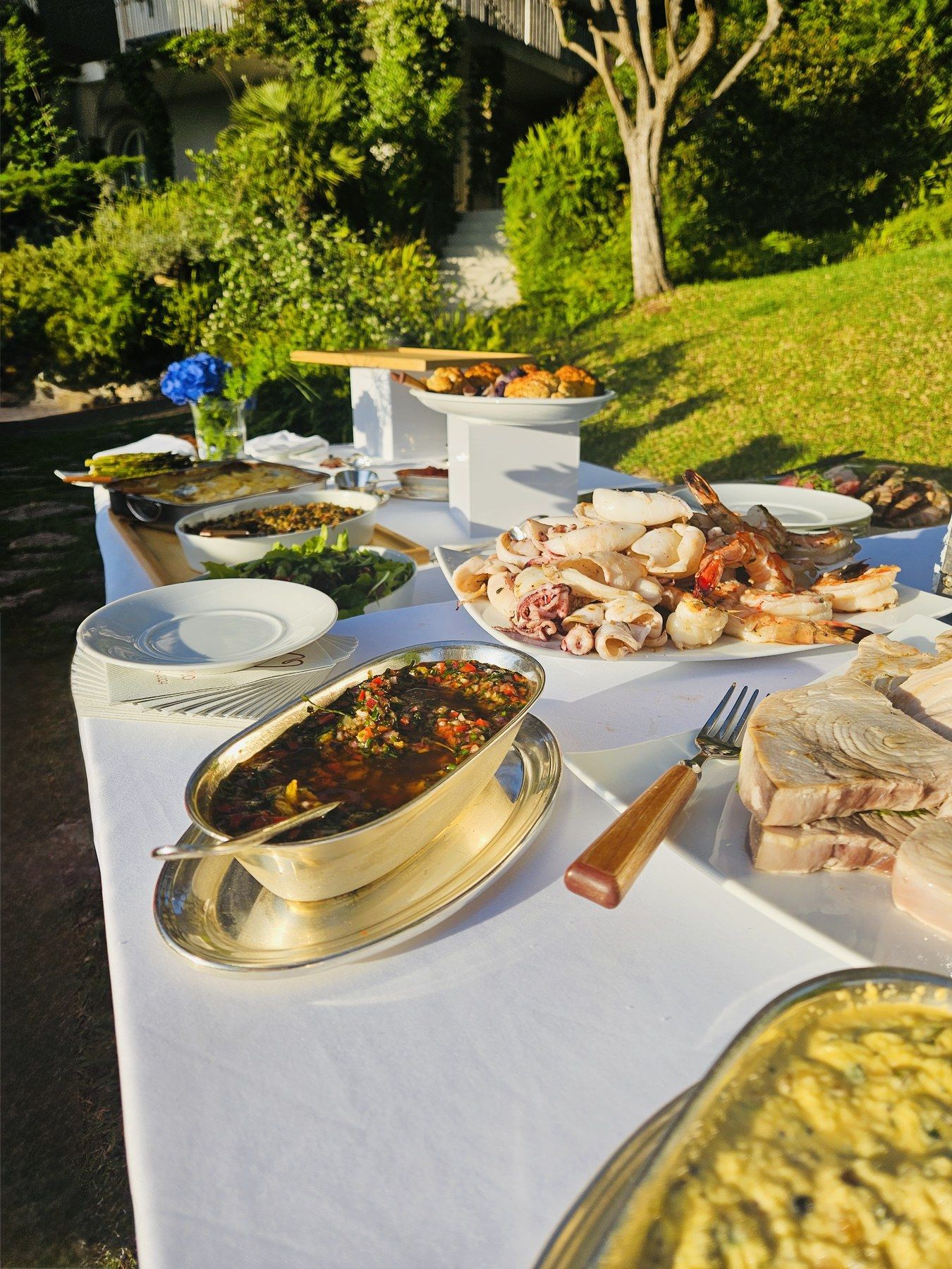 Garden buffet of sharing dishes at a villa reception.