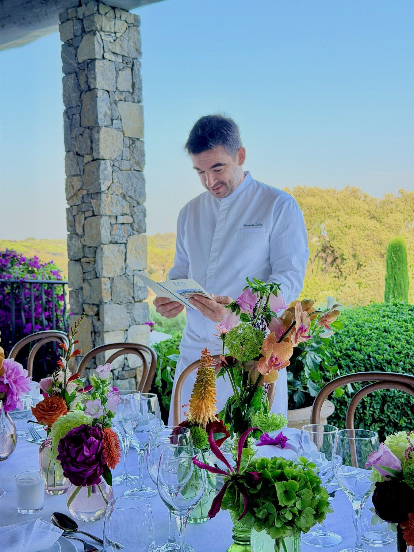 The chef reviewing the printed menu beside the flowered table.