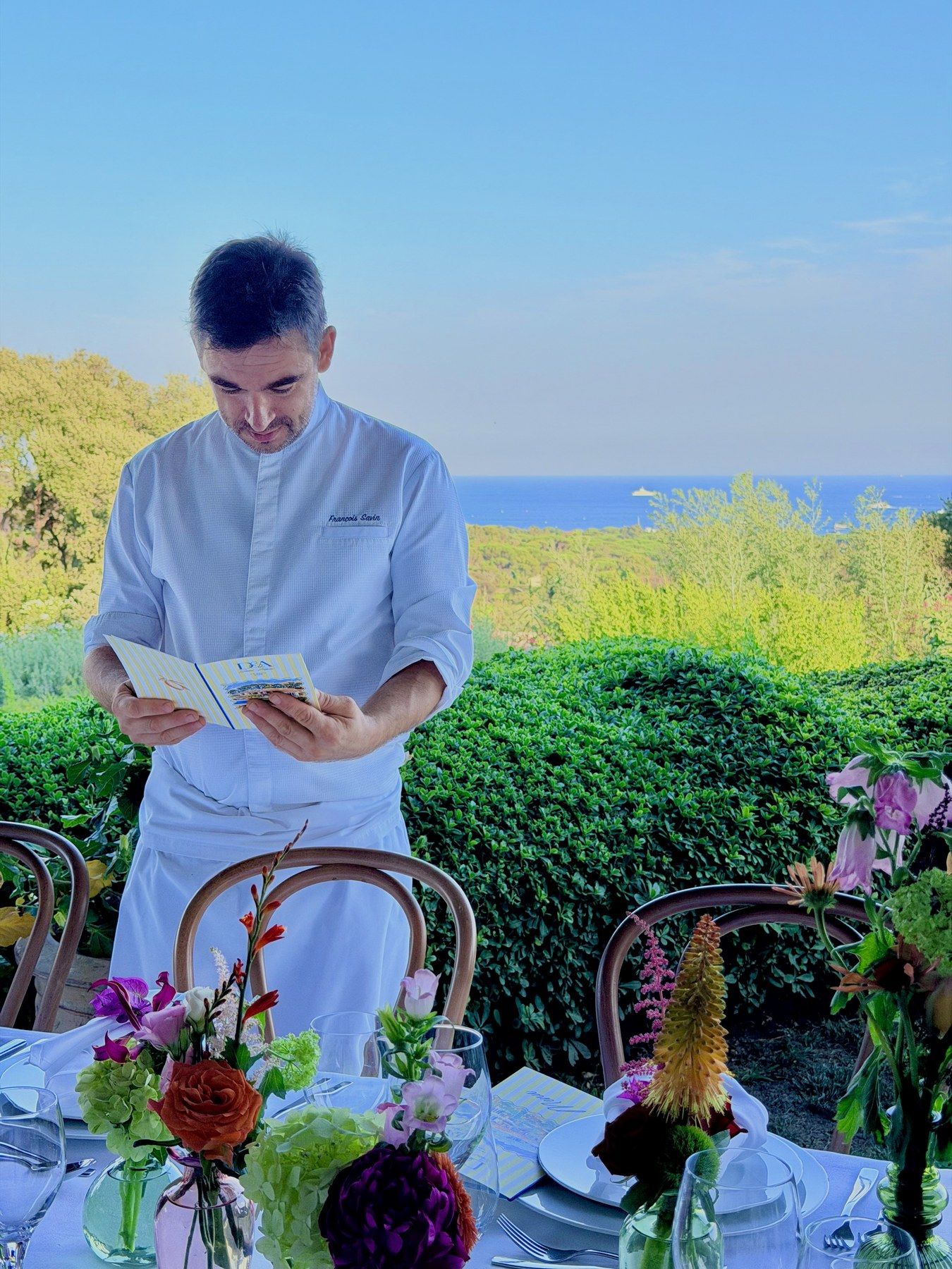 The chef checking the menu on the terrace, sea on the horizon.
