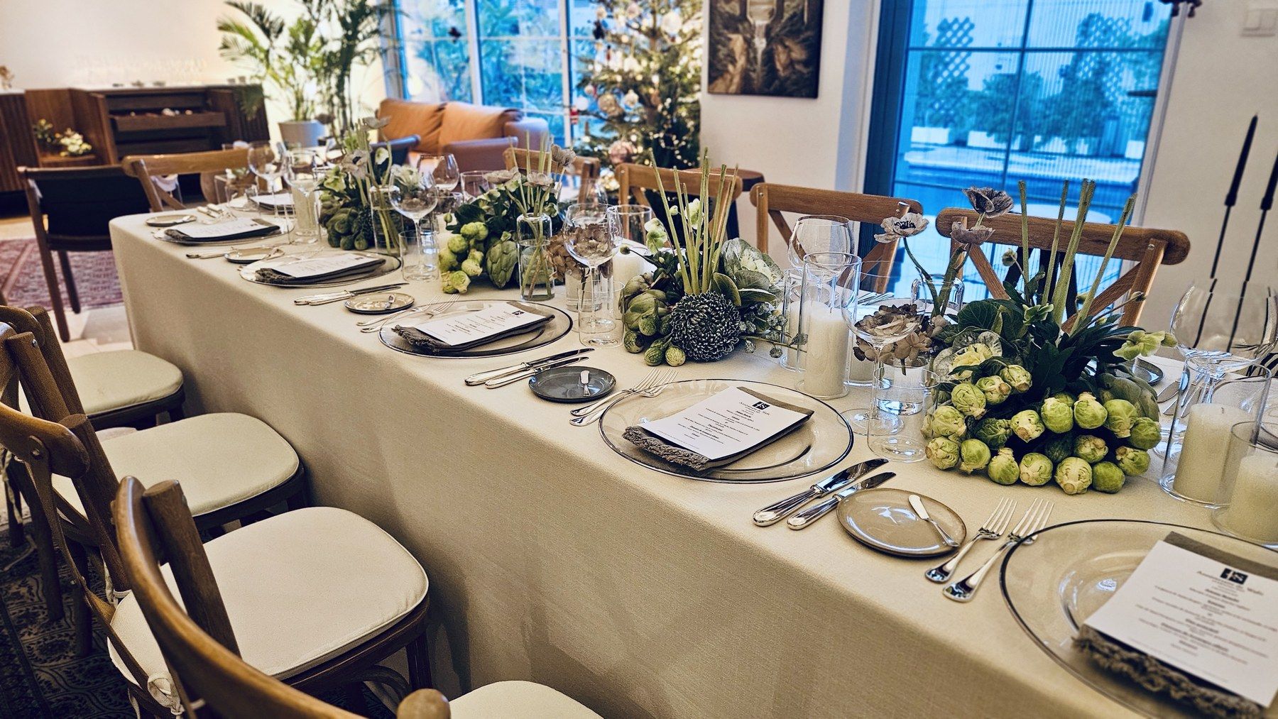 Long indoor table with artichoke centrepieces by the picture windows.