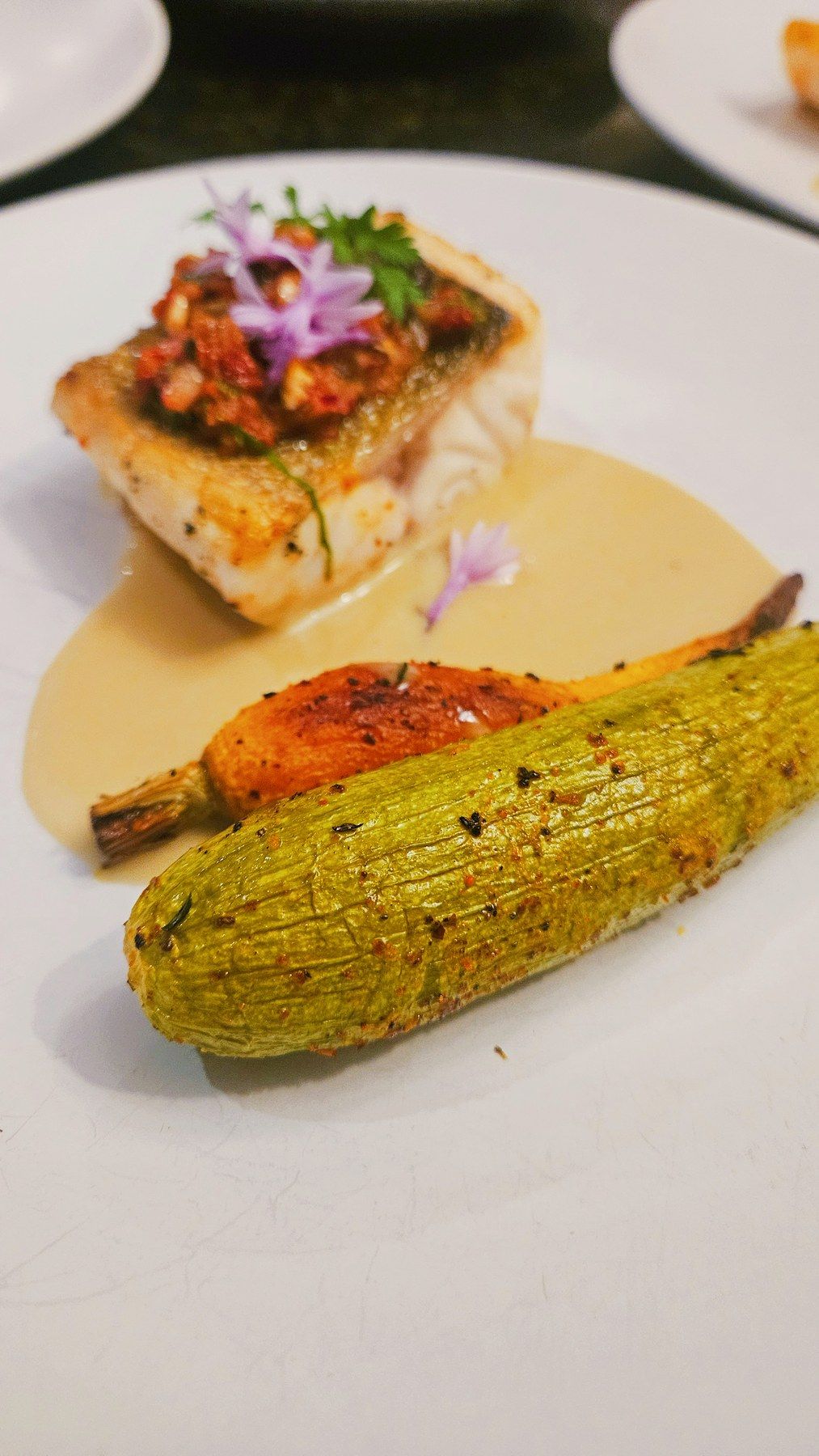 Fish fillet with a golden crust, baby courgette and cream sauce.