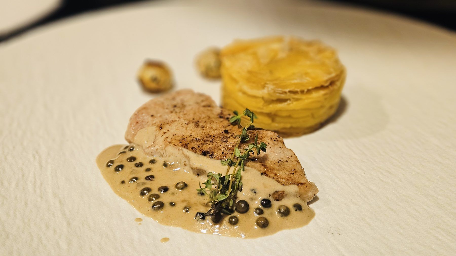 Chicken supreme with creamy dauphinois gratin and pepper jus, a main course by Chef François Savin in Antibes.
