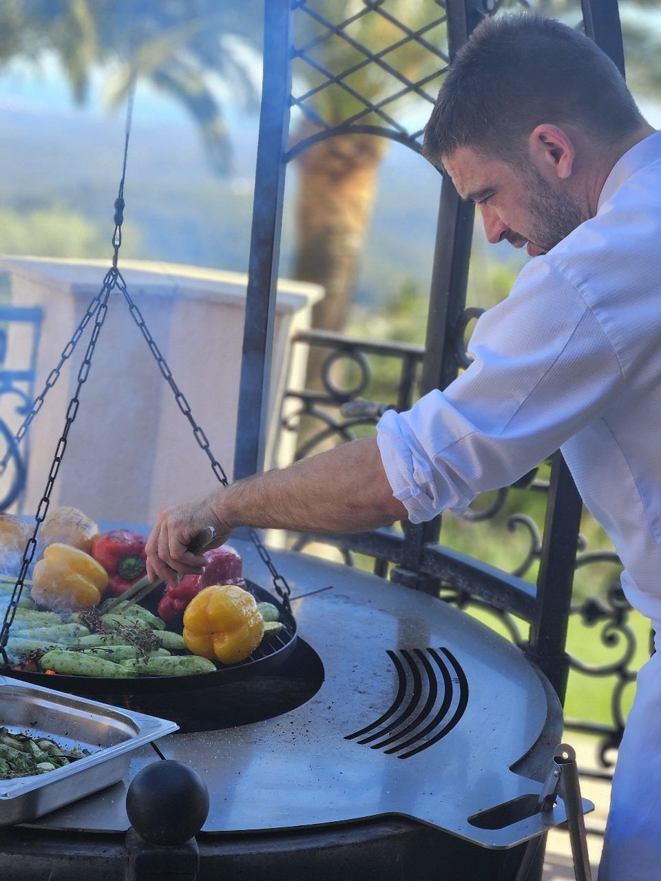 Chef François Savin grilling peppers and courgettes over open fire at a villa in Nice.
