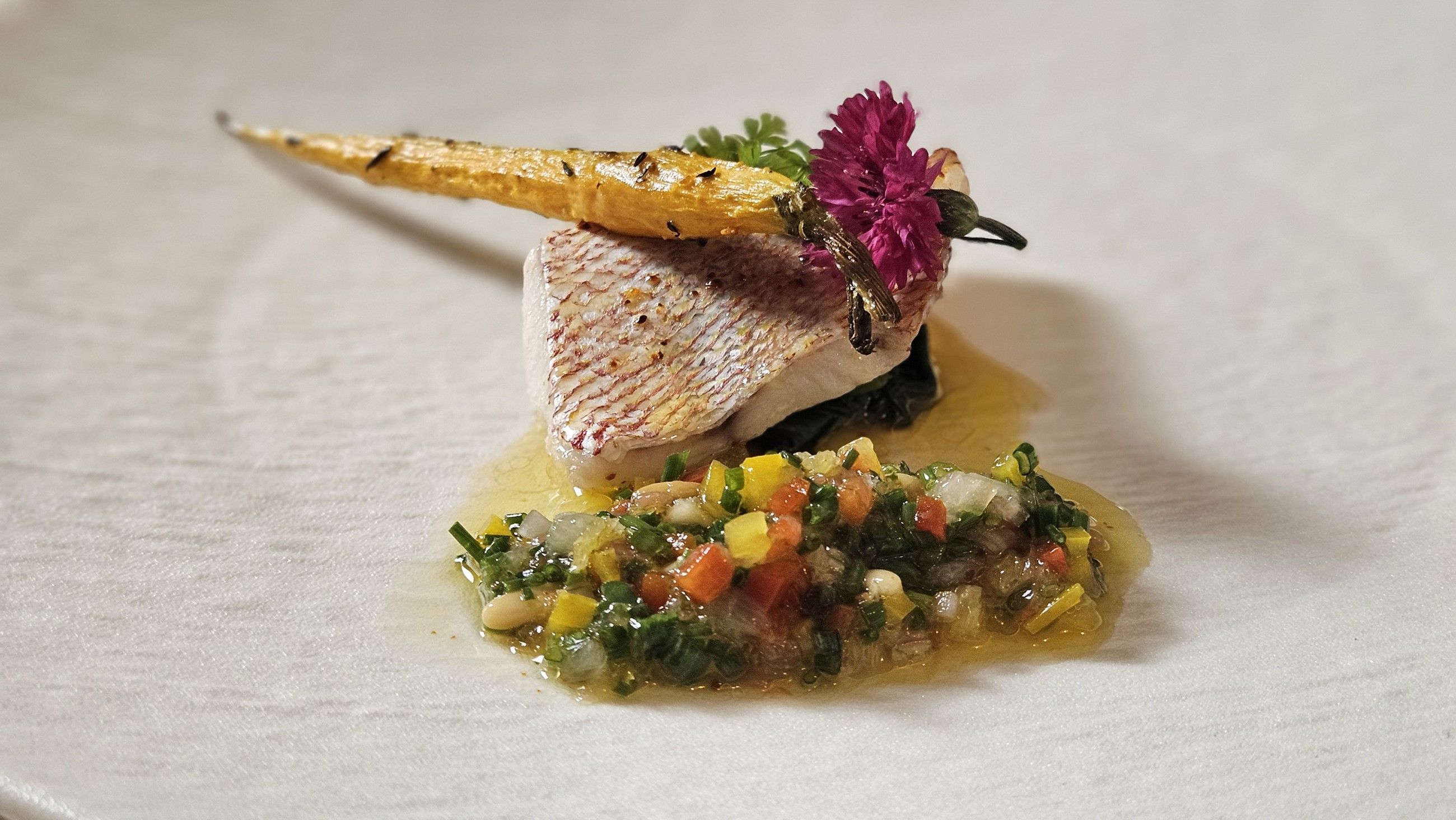 Red mullet fillet with a vegetable condiment and an edible flower.