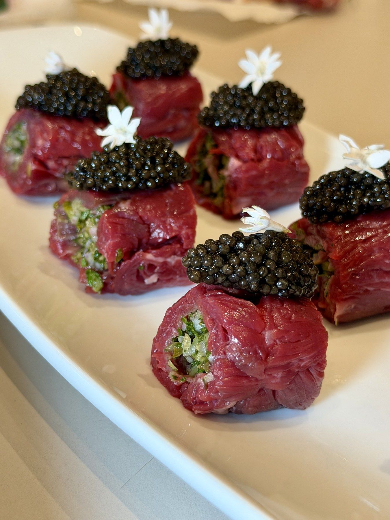 Carpaccio rolls topped with caviar, plated for service.