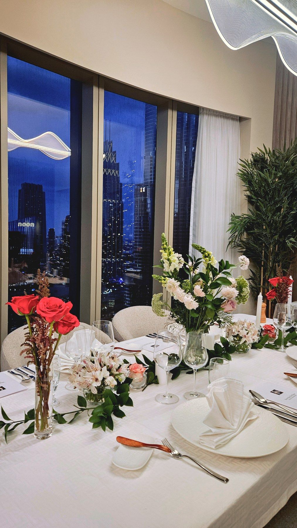 Evening table with red roses by the bay windows.