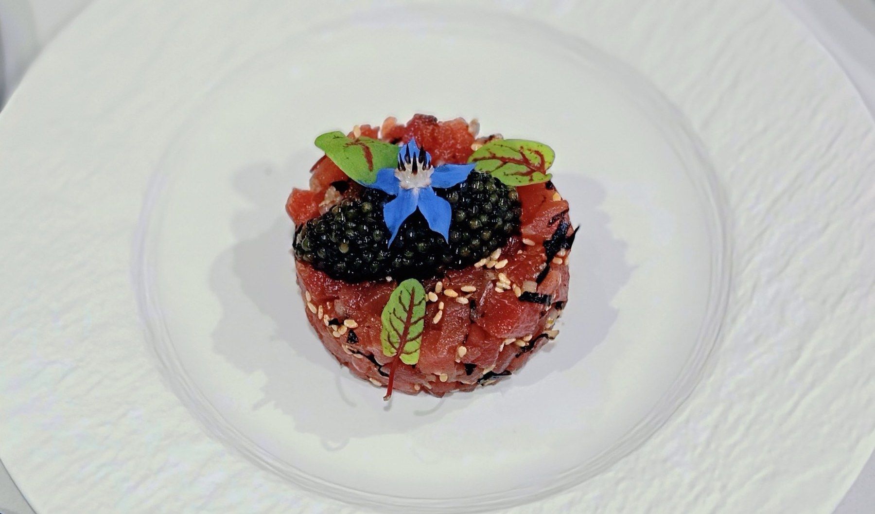 Tartare tower with berries and a borage flower.